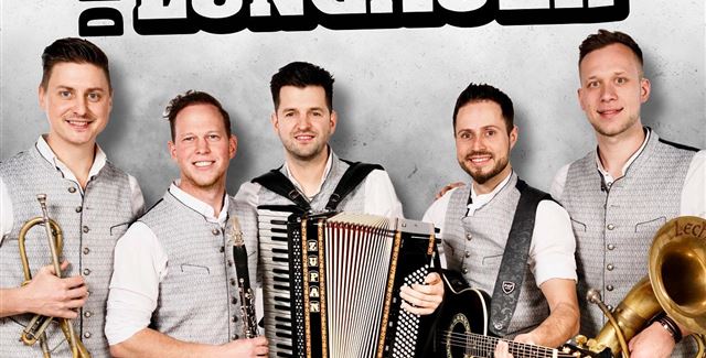A live band is playing on a stage in the mountains. In the background, there are snow-covered peaks and spectators enjoying the concert.