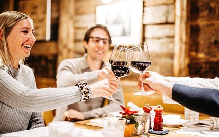 Ein fröhliches Treffen in einem gemütlichen Restaurant. Freunde stoßen mit Rotwein an und genießen die gemeinsame Zeit.