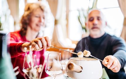 A couple enjoys a fondue in a cozy restaurant. The atmosphere is relaxed and inviting.