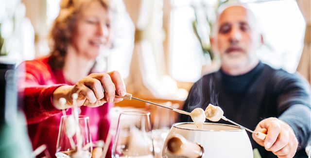 Ein Paar genießt ein Fondue in einem gemütlichen Restaurant. Die Atmosphäre ist entspannt und einladend.