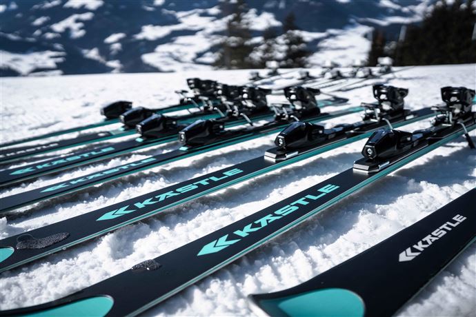 Ein Ski-Experte spricht mit einer Kundin und hält ein Paar Skier in der Hand. Im Hintergrund ist ein stylisches Sportgeschäft zu sehen.