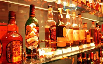 Eine Auswahl von Spirituosenflaschen in einem Regal. Die Flaschen sind gut beleuchtet und zeigen verschiedene Marken.