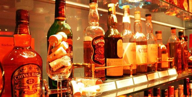 A selection of liquor bottles on a shelf. The bottles are well-lit and display different brands.