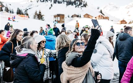 Eine lebhafte Veranstaltung in einer modernen Halle mit einer Band auf der Bühne. Die Menge jubelt und genießt die Musik.
