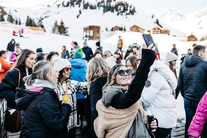 Eine lebhafte Veranstaltung in einer modernen Halle mit einer Band auf der Bühne. Die Menge jubelt und genießt die Musik.