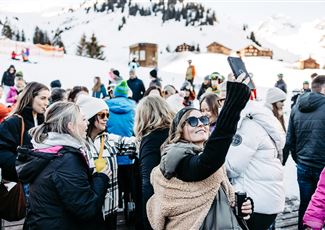 A lively event in a modern hall with a band on stage. The crowd cheers and enjoys the music.