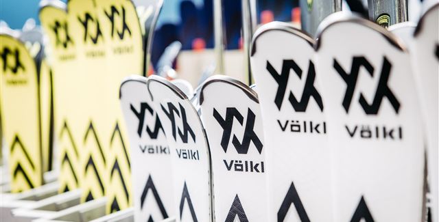 Eine Reihe von Skiern mit dem Markennamen Völkl ist ordentlich aufgereiht. Die Skier sind in verschiedenen Farben und Designs zu sehen.