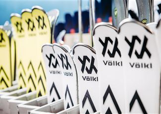 Eine Reihe von Skiern mit dem Markennamen Völkl ist ordentlich aufgereiht. Die Skier sind in verschiedenen Farben und Designs zu sehen.
