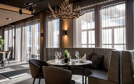 Ein modernes Restaurant mit eleganten Möbeln und großen Fenstern. Der Tisch ist für Gäste gedeckt und sorgt für eine gemütliche Atmosphäre.