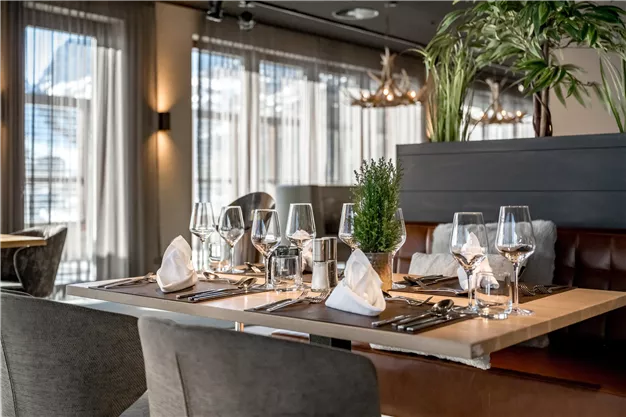 An elegantly set table in the restaurant with glasses and cutlery. The modern decor and lighting create an inviting atmosphere.
