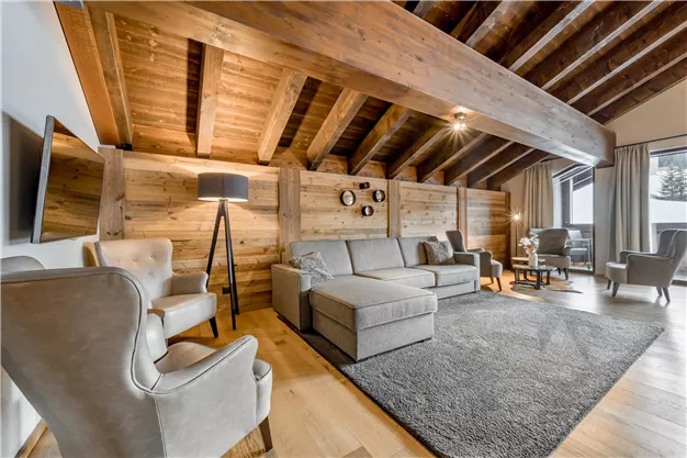 A bright and modern living room with wooden walls and a cozy sofa. The room is decorated with stylish furniture and inviting lighting.