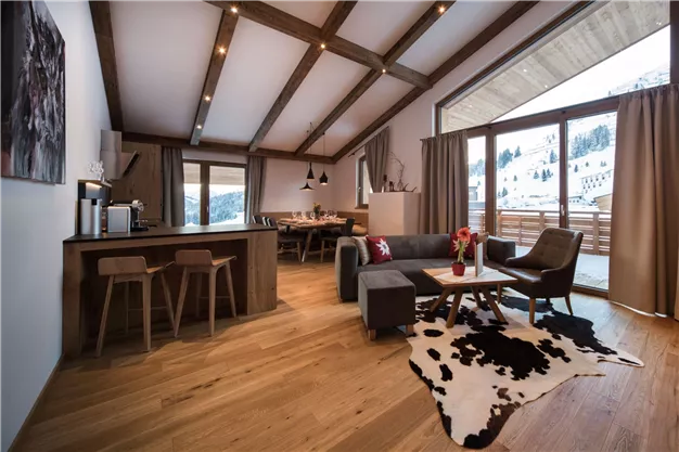 Eine moderne Wohnung mit Holzfußboden und großen Fenstern. Der Raum ist hell und gemütlich, mit einer offenen Küche und stilvollen Möbeln.