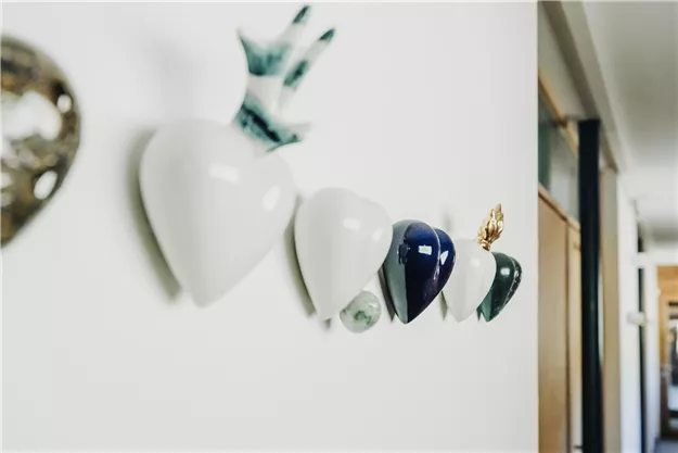 Eine dekorative Wand mit verschiedenen herzförmigen Keramiken in unterschiedlichen Farben. Die Objekte sind elegant angeordnet und verleihen dem Raum eine moderne Note.