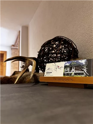 A table with a decorative bowl, an antler, and a card holder. There are business cards visible with information about an accommodation.