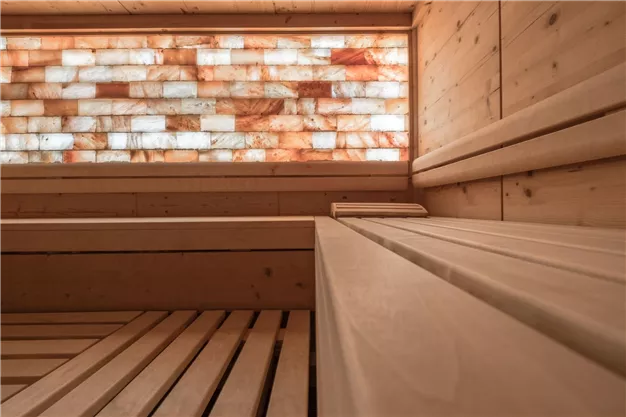 Eine moderne Sauna mit Holzregalen und einem dekorativen Salzwand. Der Raum strahlt eine entspannende Atmosphäre aus.