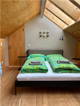 A cozy bedroom with a double bed and colorful blankets. The skylights provide plenty of daylight and a pleasant atmosphere.