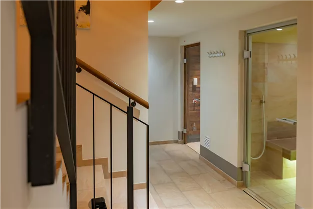 A modern, bright hallway with wooden and tiled flooring. On the right is access to a bathroom with a shower.